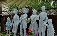 Custom Chicken Wire sculptures of people in a garden setting with plants and flowers.